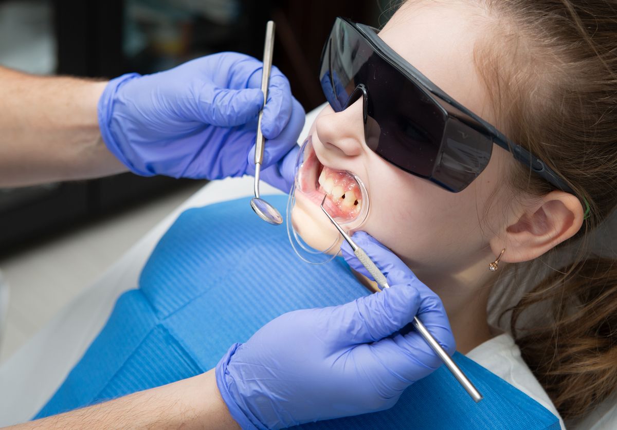 Dentist examining a child's teeth with dental tools at a checkup