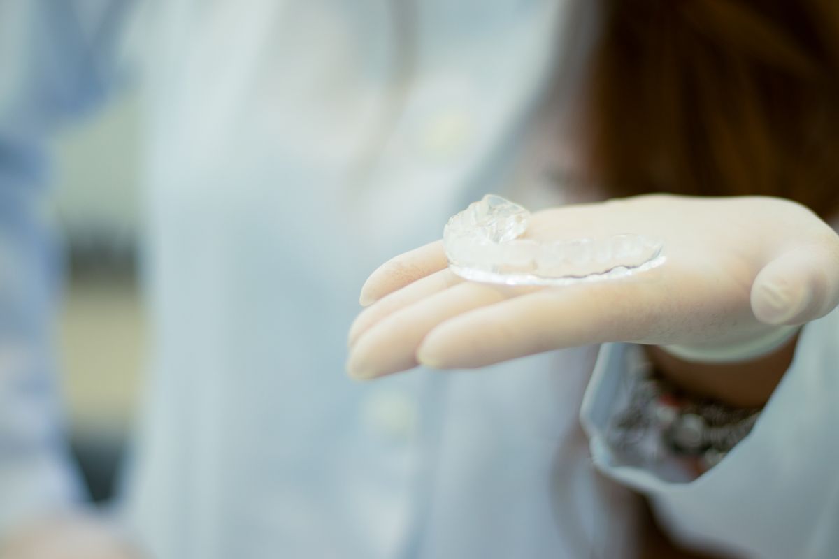 Cracked Tooth: Signs, Causes, and How Dentists Fix It 4 Gloved hand holding a clear night guard used to protect teeth from grinding and cracks