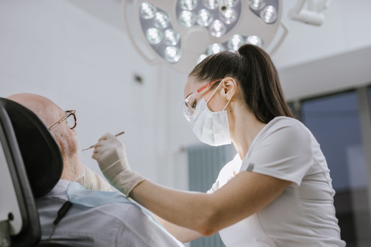 Cracked Tooth: Signs, Causes, and How Dentists Fix It 3 Female dentist examining an older patient in a bright dental office